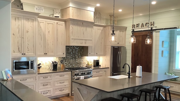 A kitchen with wooden cabinets, a central island with stools, a refrigerator, a stove, and pendant lighting. - Stunning five bedroom home with private pool, just steps from the beach! (Panama City Beach)