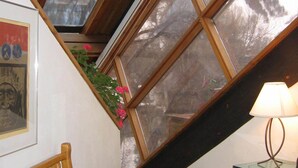 Une pièce avec un plafond en pente, des poutres en bois, une table en verre et une chaise.