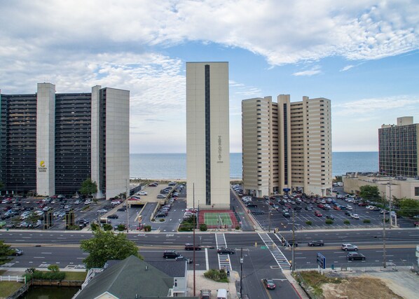 A high-rise building with a central tower, parking lots, and a view of the sea.