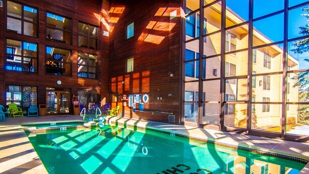 A modern indoor swimming pool with clear glass walls, surrounded by wooden paneling and large windows. - Brian Head Penthouse South, Pool-Hotub, Ski-i/o, 3 Masters, Play lofts, Sleep 14 (Brian Head)