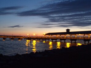 A pier extending into the water with a covered walkway and a small structure at the end.