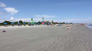 Une plage avec des parasols, des chaises longues et des gens.