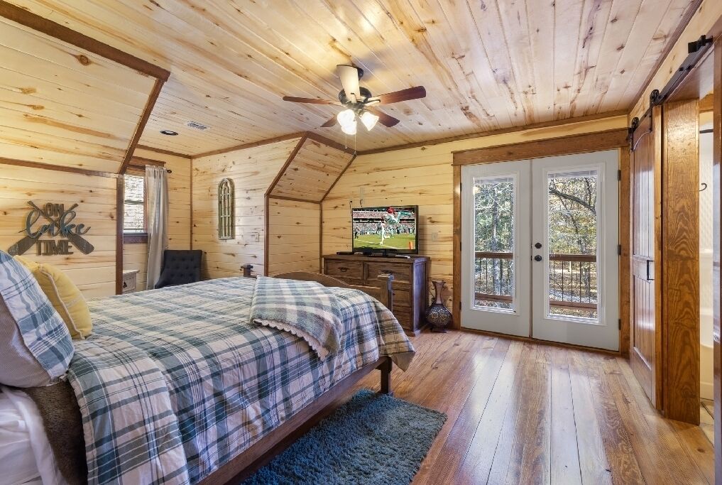 A cozy bedroom with a bed, a television, and a large window.