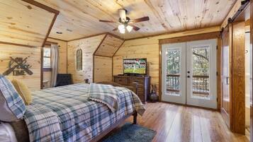 A cozy bedroom with a bed, a television, and a large window.