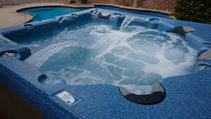 Uma banheira de hidromassagem com vários jatos, cercada por uma borda de pedra e uma moldura de azulejos.