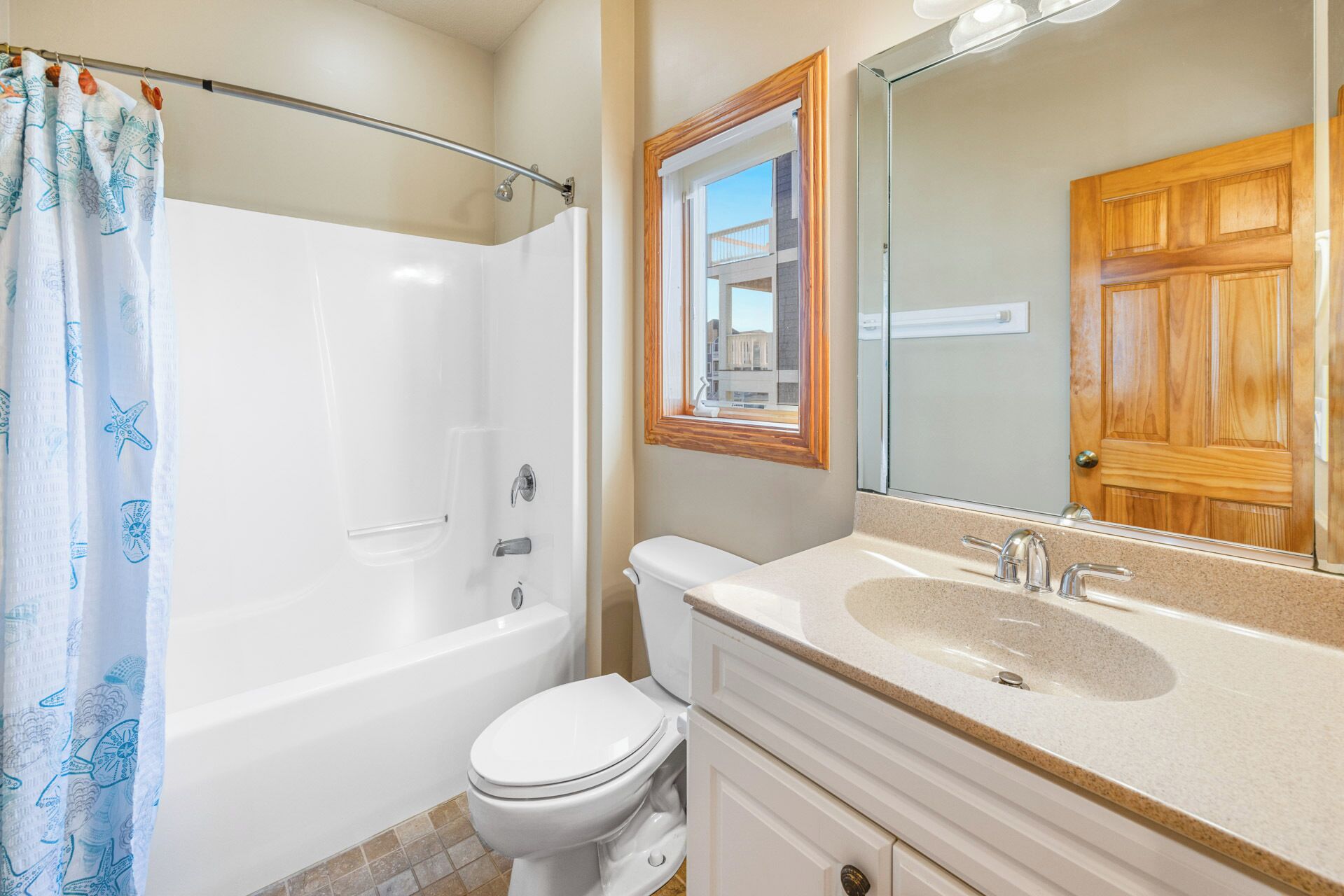 A bathroom with a bathtub, toilet, vanity with a sink, and a mirror.