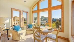 A sunlit room with a large window, a round table, and two sofas. - Semi-Oceanfront Dog Friendly w/ Pool, Hot Tub, Elevator, Theater, and Game Room (Salvo)