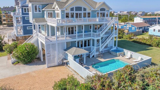 A multi-story beachfront house with a pool, balconies, and a view of the ocean. - Semi-Oceanfront Dog Friendly w/ Pool, Hot Tub, Elevator, Theater, and Game Room (Salvo)