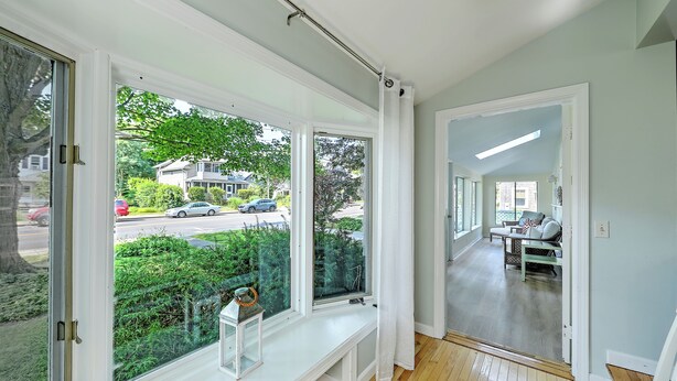 Ein Zimmer mit großen Fenstern, einer Bank und Blick auf die Straße sowie auf Grünflächen.