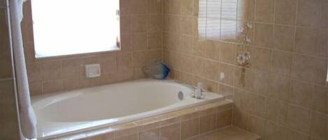 A bathroom with a bathtub, toilet, and a window.