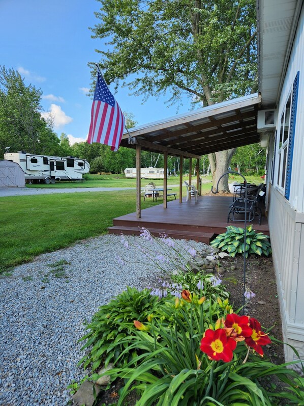 A covered patio area with outdoor seating, a flag, and a recreational vehicle in the background.