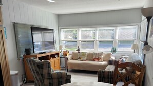 A cozy living room with a sofa, chairs, a TV, and a dining table. - Seasonal Fully Furnished Mobile home (Port Austin)