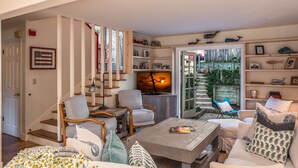 A cozy living room with a fireplace, comfortable seating, and a staircase leading to a balcony.