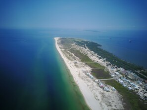 An aerial view of a coastal area with a long sandy beach, a marina with boats, and a resort with multiple buildings along the shore. - Book now for Fall 2026! Pet friendly! (Gulf Shores)