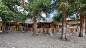 A rustic lodge with a stone-paved courtyard, wooden cabins, and a large bear statue. - Yosemite! Dogs & family! Mountain Air, come visit and make Wonderful Memories! (Oakhurst)