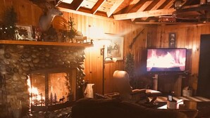 A cozy living room with a stone fireplace, wooden walls, a television, and a comfortable sofa. - Yosemite! Dogs & family! Mountain Air, come visit and make Wonderful Memories! (Oakhurst)