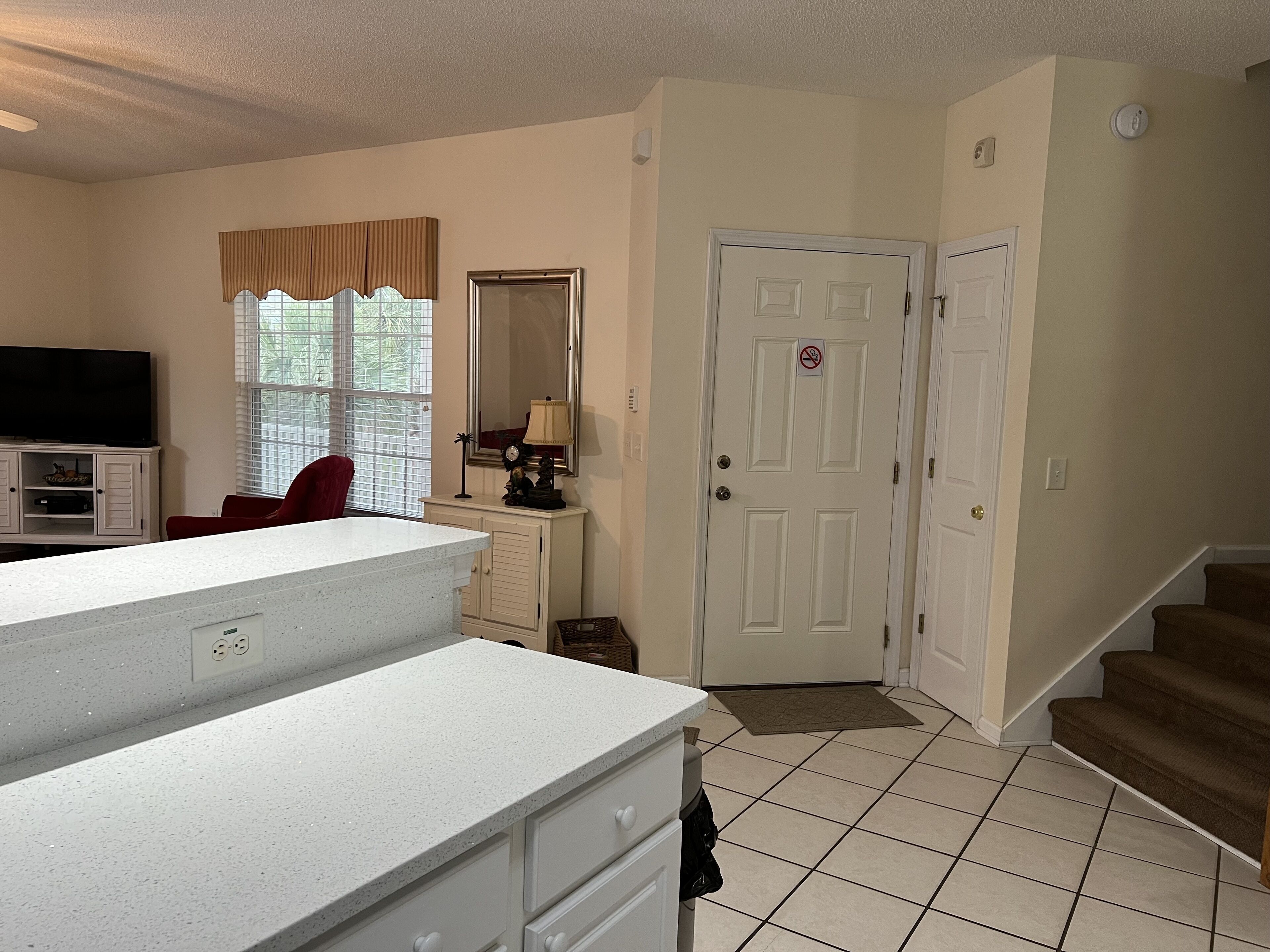 A well-lit room with a kitchen counter, a dining area, and a staircase.