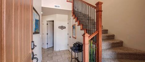 A staircase with wooden railings and a carpeted floor leading to a room with a piano.