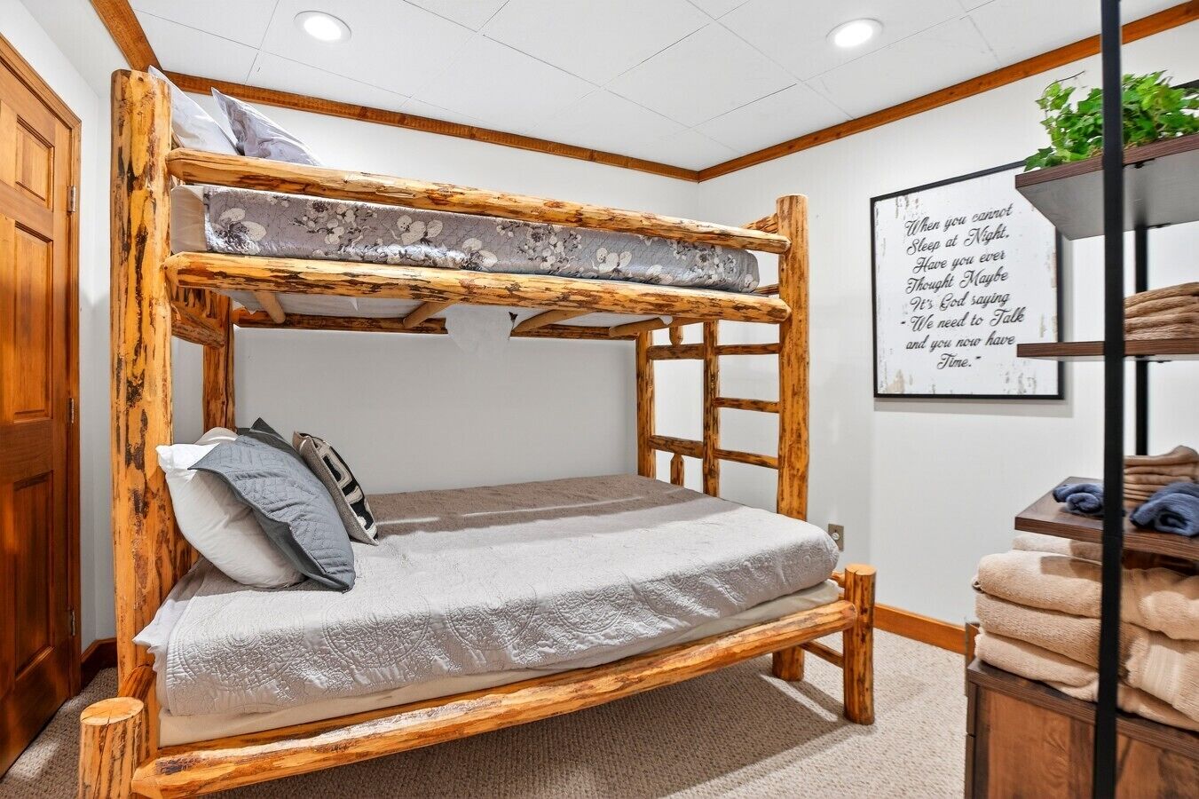 A bunk bed with a wooden frame and a lower bed with a white quilt.