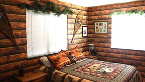 Un dormitorio de estilo cabaña de madera con una cama, una mesita de noche y una ventana con persianas.