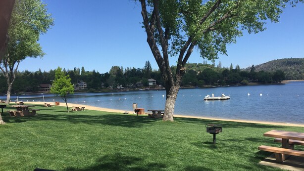 Un parque junto al lago con mesas de picnic, un muelle para embarcaciones y una vista despejada del lago.