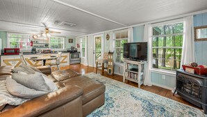 A spacious living room with a leather sofa, a television, and a fireplace. - Forget-Me-Knot Cottage at The Wilderness of Mentone adjoins the LRCNP (Mentone)