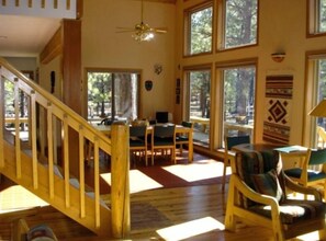 A spacious room with a wooden staircase, large windows, and a dining area. - Black Butte Ranch Mountain Style Home (Black Butte Ranch)