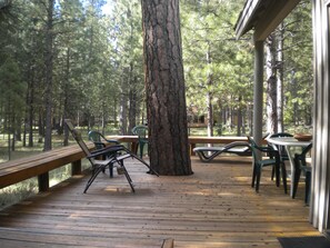 A wooden deck with benches and tables, surrounded by trees. - Black Butte Ranch Mountain Style Home (Black Butte Ranch)