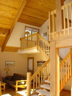A wooden interior with a staircase, a sofa, and a window. - Black Butte Ranch Mountain Style Home (Black Butte Ranch)