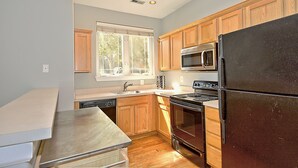 Una cocina con armarios de madera, electrodomésticos de acero inoxidable, una ventana y una encimera.