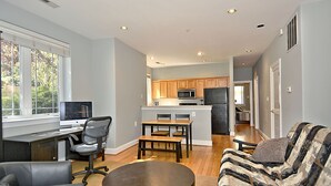 Una sala de estar moderna con comedor, cocina y un ventanal grande.