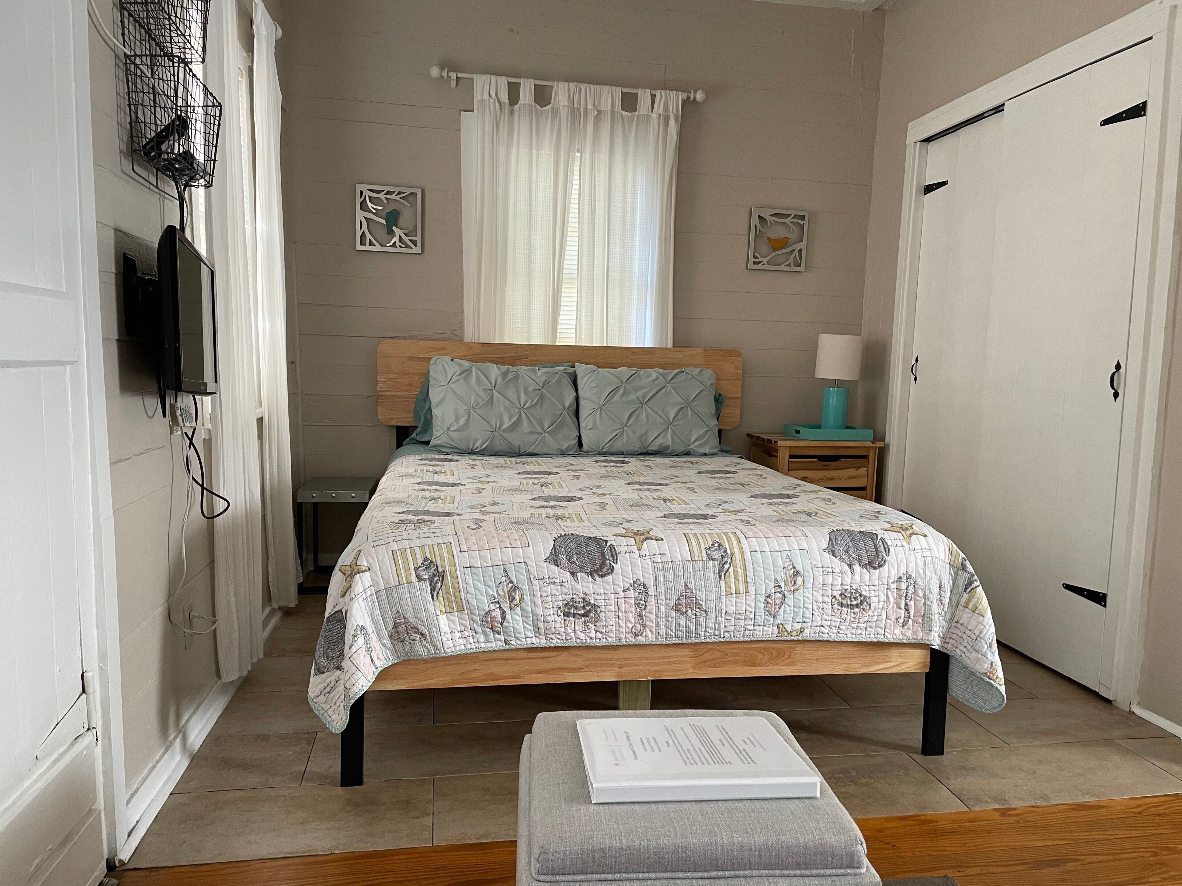A bedroom with a bed, bedside table, lamp, and a book on a small table.