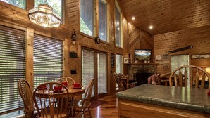 Un intérieur en bois comprenant un coin repas, une cuisine et une cheminée.