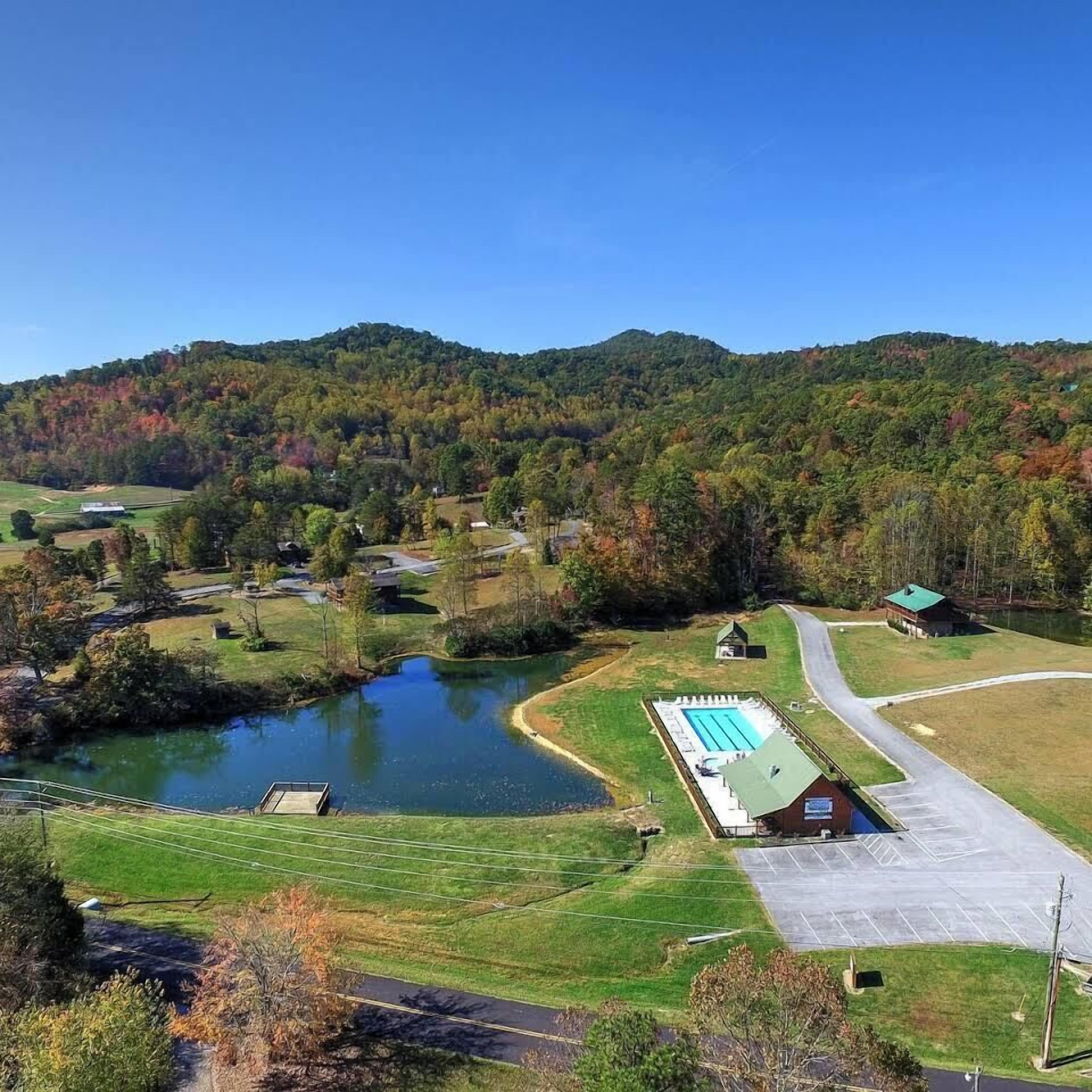 Un grand bâtiment doté d’une piscine, entouré d’un parking et d’un petit étang.