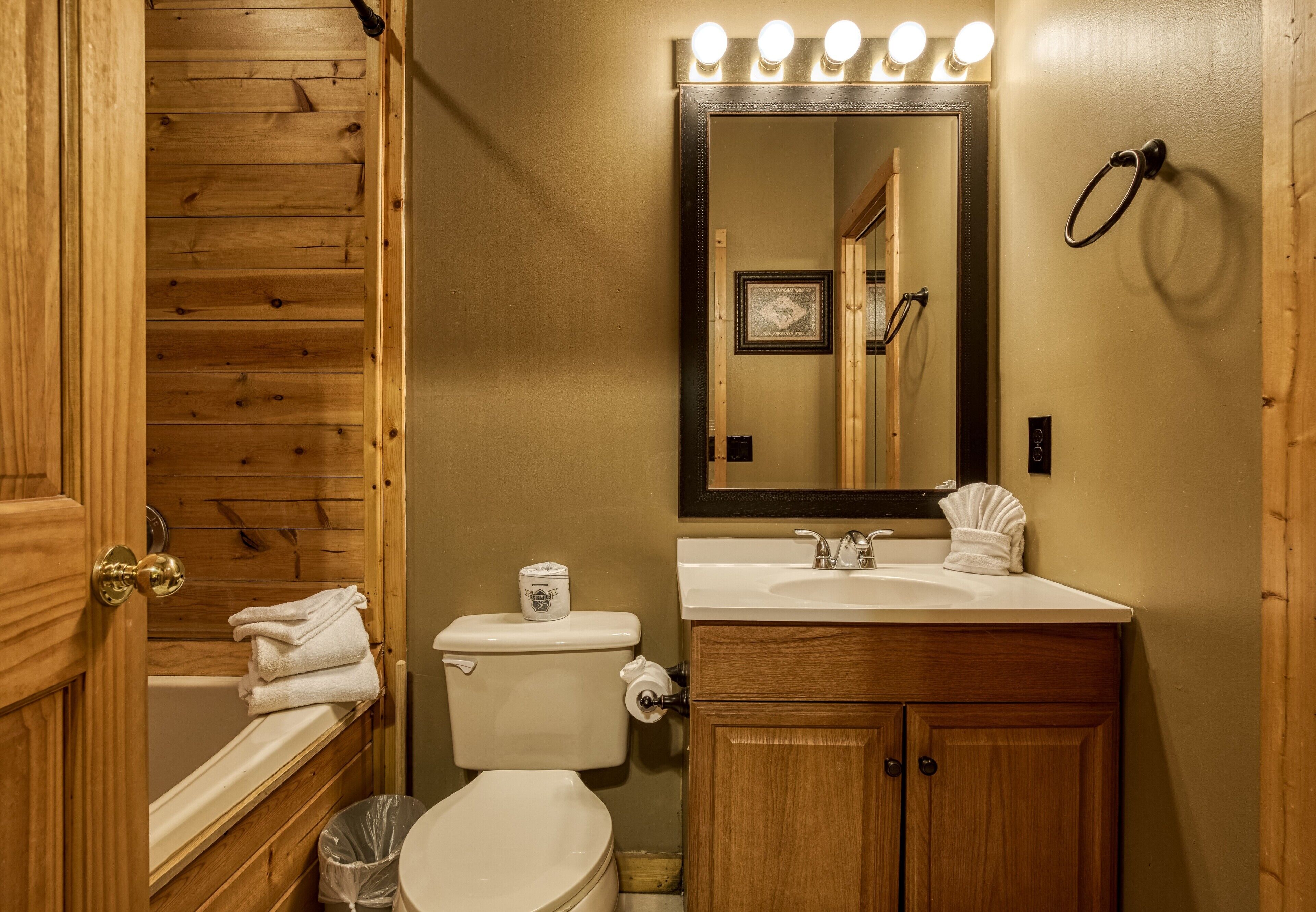 A bathroom with wooden paneling, a white toilet, a sink with a mirror above it, and a towel rack.