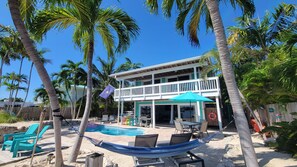 A two-story house with a pool, surrounded by palm trees and a sandy beach. - 🌴 Coco Plum Paradise 🌴 Private Bayfront Home • Pool • Hot Tub • Dock • View (Marathon)