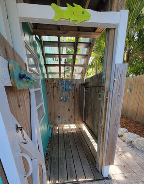 A wooden outdoor shower area with a wooden door, a metal showerhead, and a wooden bench. - 🌴 Coco Plum Paradise 🌴 Private Bayfront Home • Pool • Hot Tub • Dock • View (Marathon)