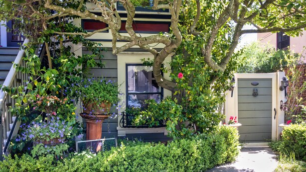 A residential building with a front porch, a potted plant, and a small garden area. - Garden Apartment Located in a Wonderful Old Victorian Home (Alameda)