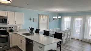 A modern kitchen with white cabinets, stainless steel appliances, and a central island with seating. - Amazing Ocean & Bay Views Beach access is feet away Heated Pool Hot Tub Tiki Bar (North Topsail Beach)