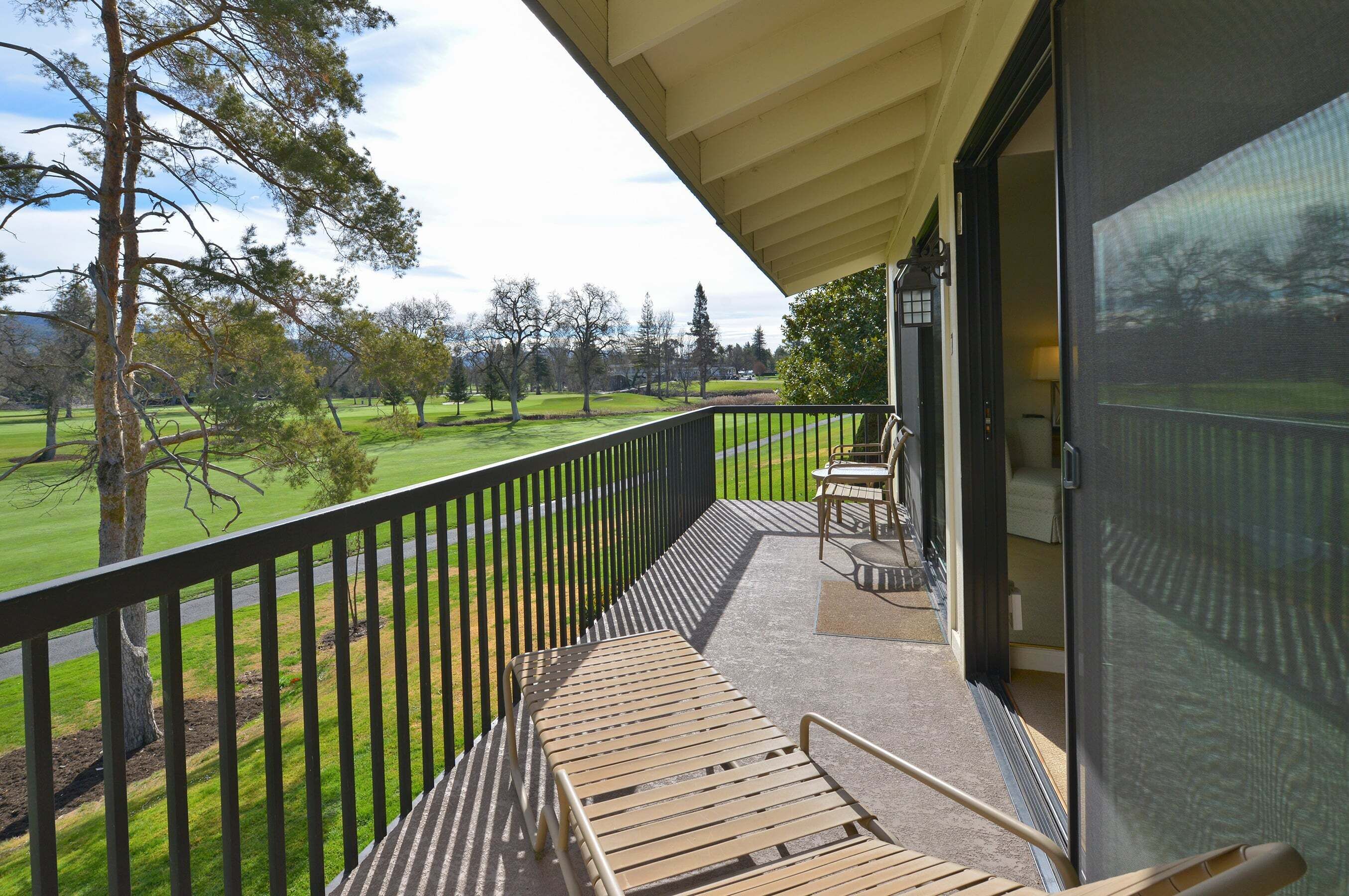 A balcony with a view of a green landscape and trees.