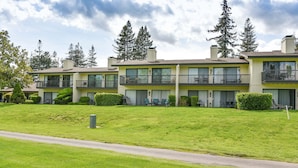 A multi-story residential building with balconies, a well-maintained lawn, and a clear sky.
