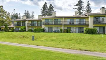 A multi-story residential building with balconies, a well-maintained lawn, and a clear sky.