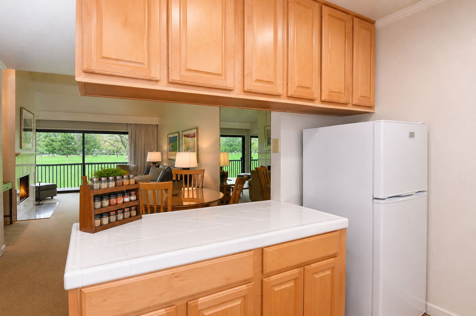 A kitchen with wooden cabinets, a white countertop, and a white refrigerator.