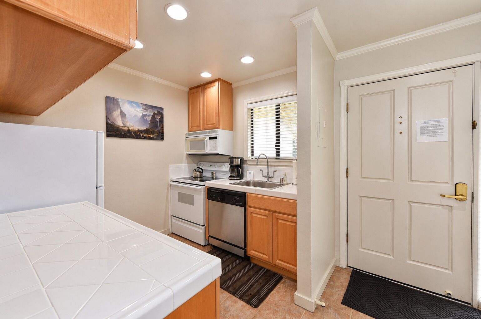 A compact kitchen with white cabinetry, a microwave, a stove, and a sink.