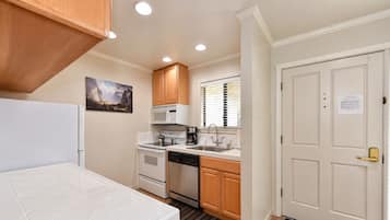 A compact kitchen with white cabinetry, a microwave, a stove, and a sink.