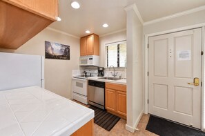 A compact kitchen with white cabinetry, a microwave, a stove, and a sink.