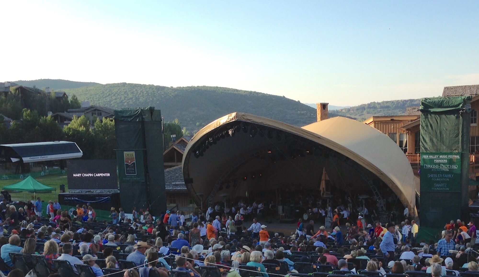 A large outdoor amphitheater with a curved stage, surrounded by a crowd of spectators.