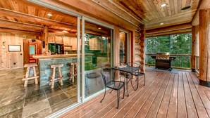 A wooden cabin with a kitchen, bar area, and a deck with a grill. - Crest Lodge - 3,700sf Log Home with 5 bedrooms + Sleeps 15-17 (Ronald)
