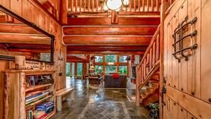 A wooden interior with a fireplace, bookshelves, and a staircase. - Crest Lodge - 3,700sf Log Home with 5 bedrooms + Sleeps 15-17 (Ronald)