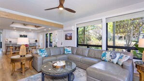 A modern living room with a sectional sofa, a round coffee table, and a dining area with wooden furniture.